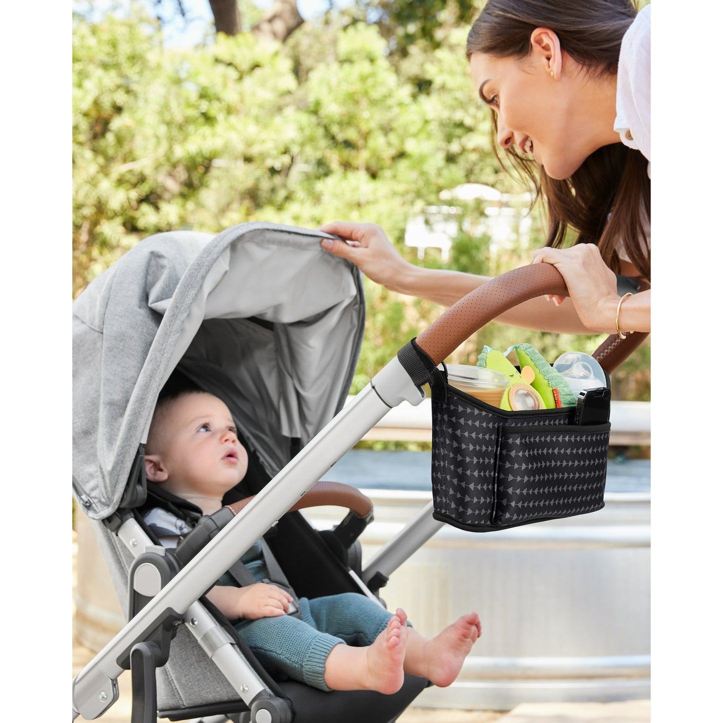 Image dispalying a baby in a baby stroller and  a woman holidng a baby stroller accessory