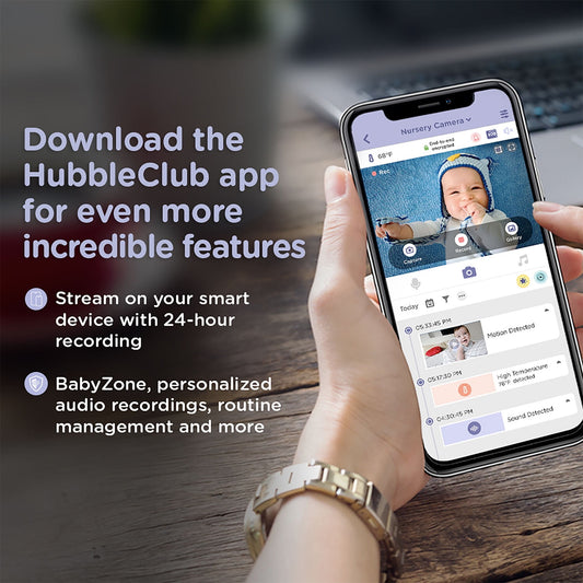 A hand holds a smartphone displaying a baby monitor app interface, promoting app features for a baby monitor system