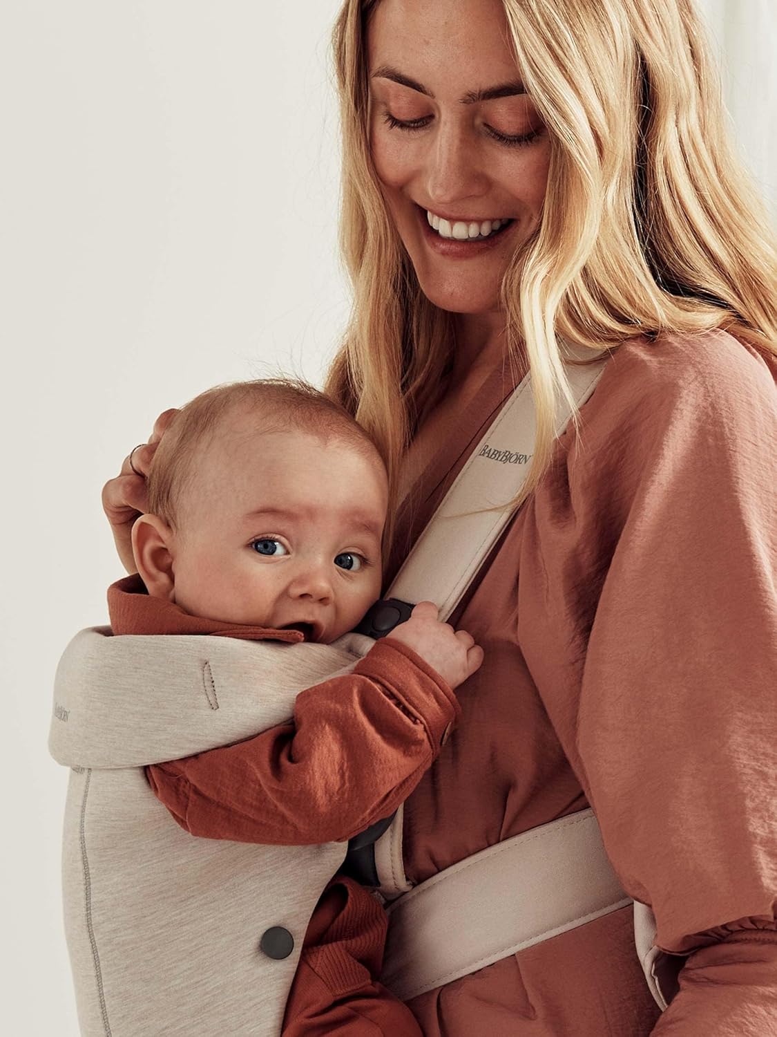 Image displaying a woman and a baby in a baby carrier and text about it's details