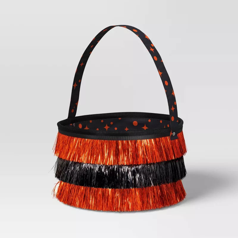 Black and orange Halloween candy basket with fringed design on a light gray background