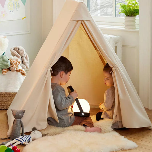 Two children are inside a fabric play tent, with one holding a glowing lantern