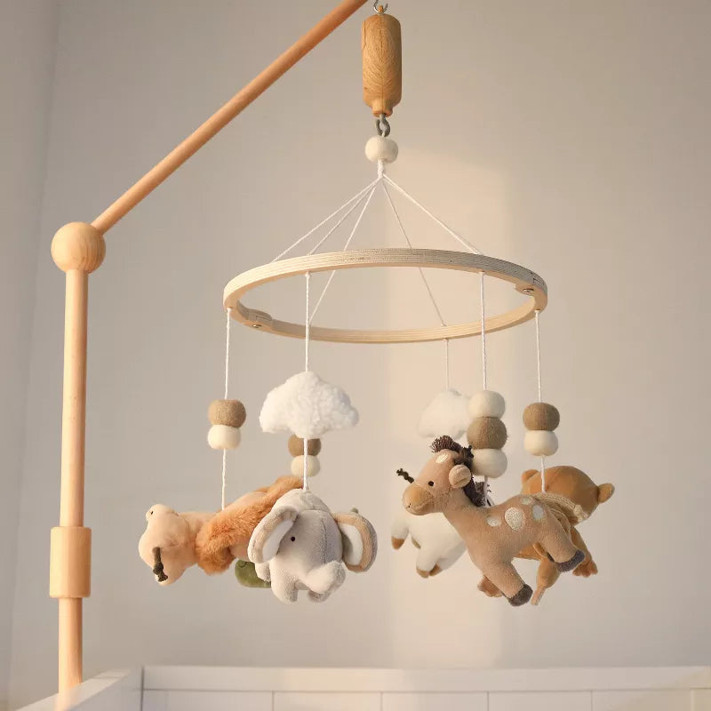 A wooden baby crib mobile hangs with plush safari animals and clouds, serving as nursery décor