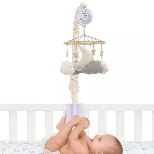 A baby lies beneath a baby crib mobile featuring a moon, stars and clouds, with a white Background