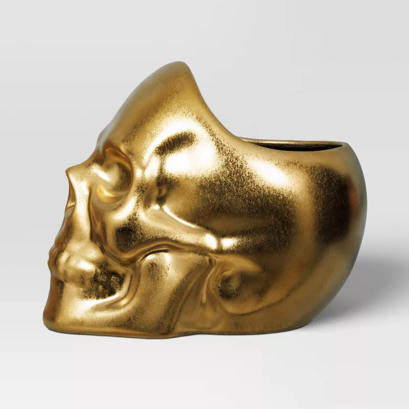 Halloween Themed Gold skull-shaped pot on a light gray background