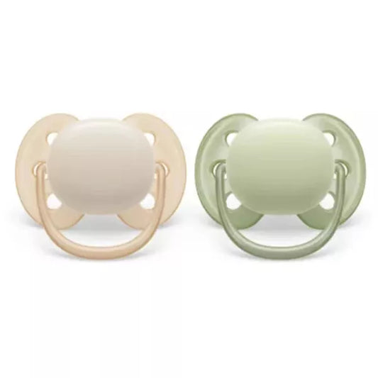 Two baby pacifiers, one beige and one green, on a white background