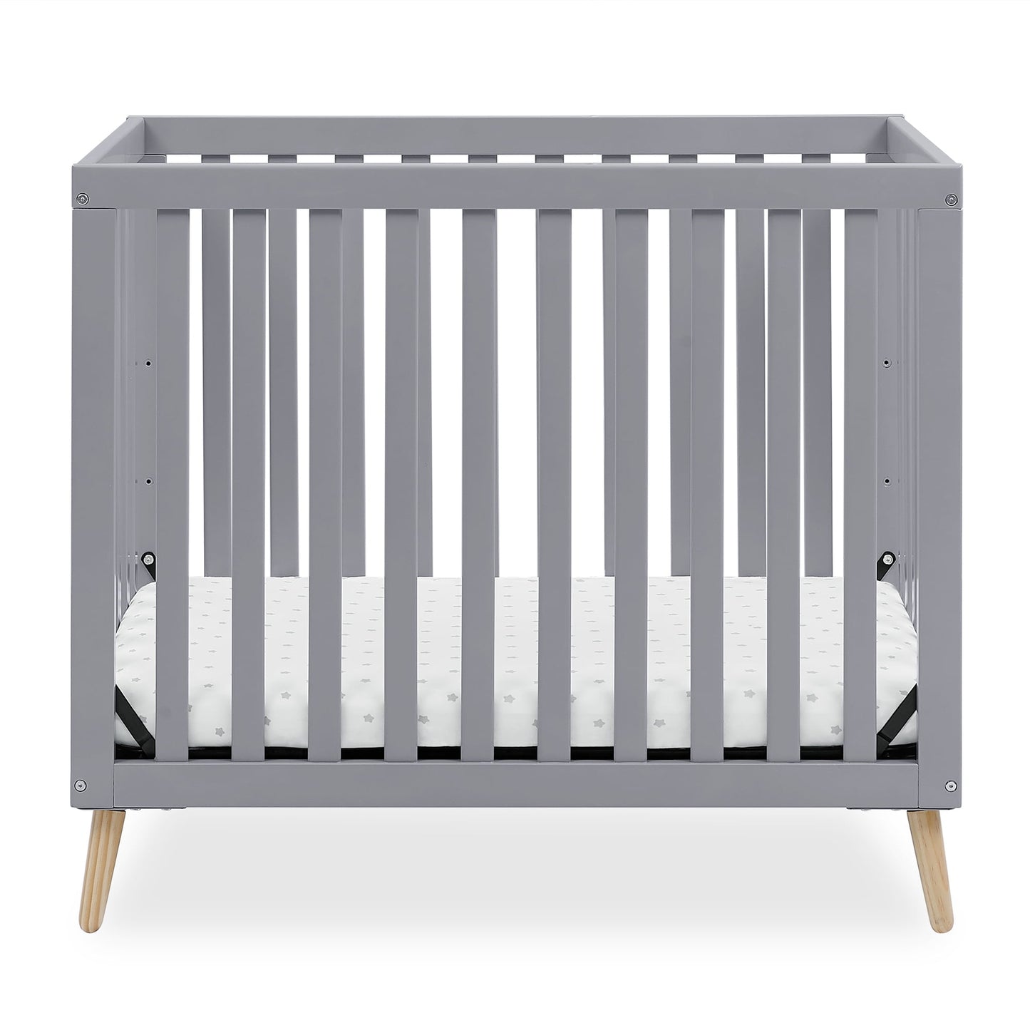 A grey baby crib with a white mattress, featuring natural wood splayed legs
