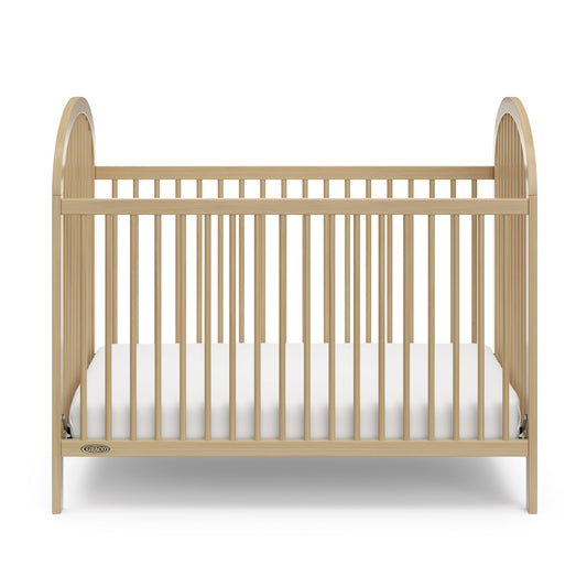 A wooden baby crib with a white mattress, designed for infants and toddlers