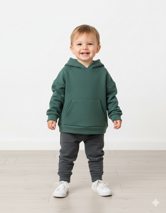 Child wearing a green hoodie and gray pants on a white background