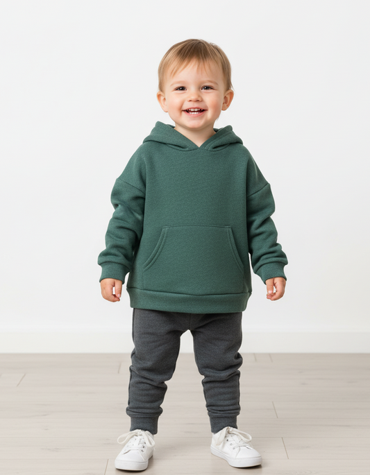 Child wearing a green hoodie and gray pants on a white background