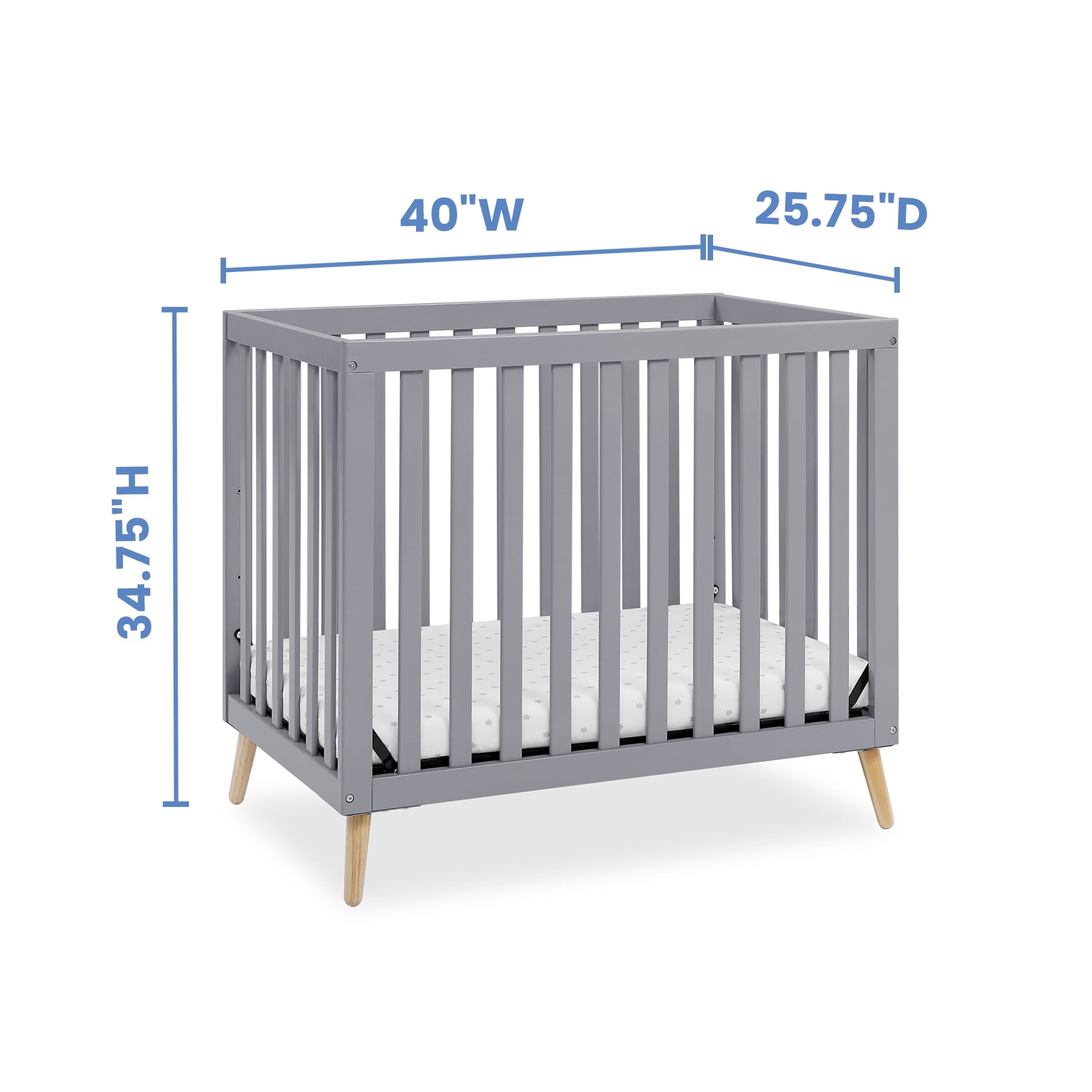 A gray baby crib with natural wood legs and mattress, displaying height, width, and depth dimensions