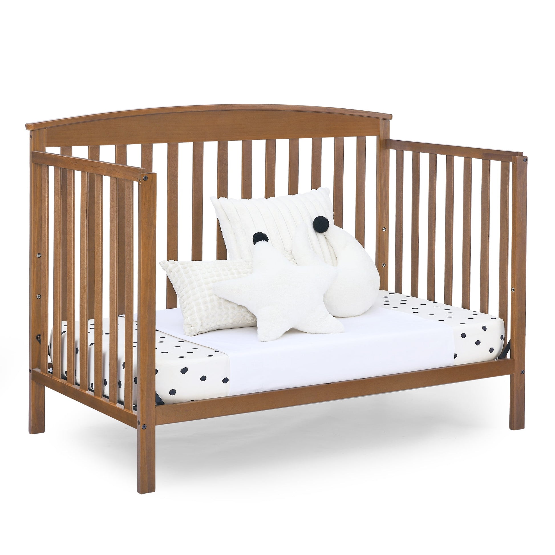 A wooden baby crib with a mattress and decorative pillows inside, ready for a child