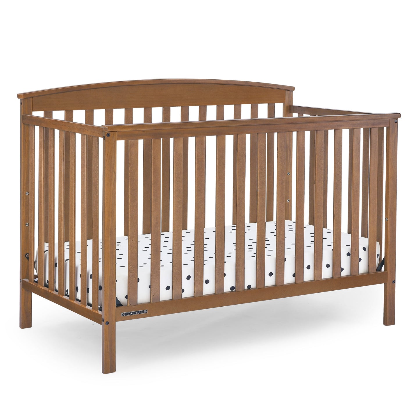 A wooden baby crib with a mattress featuring a white and black polka dot pattern