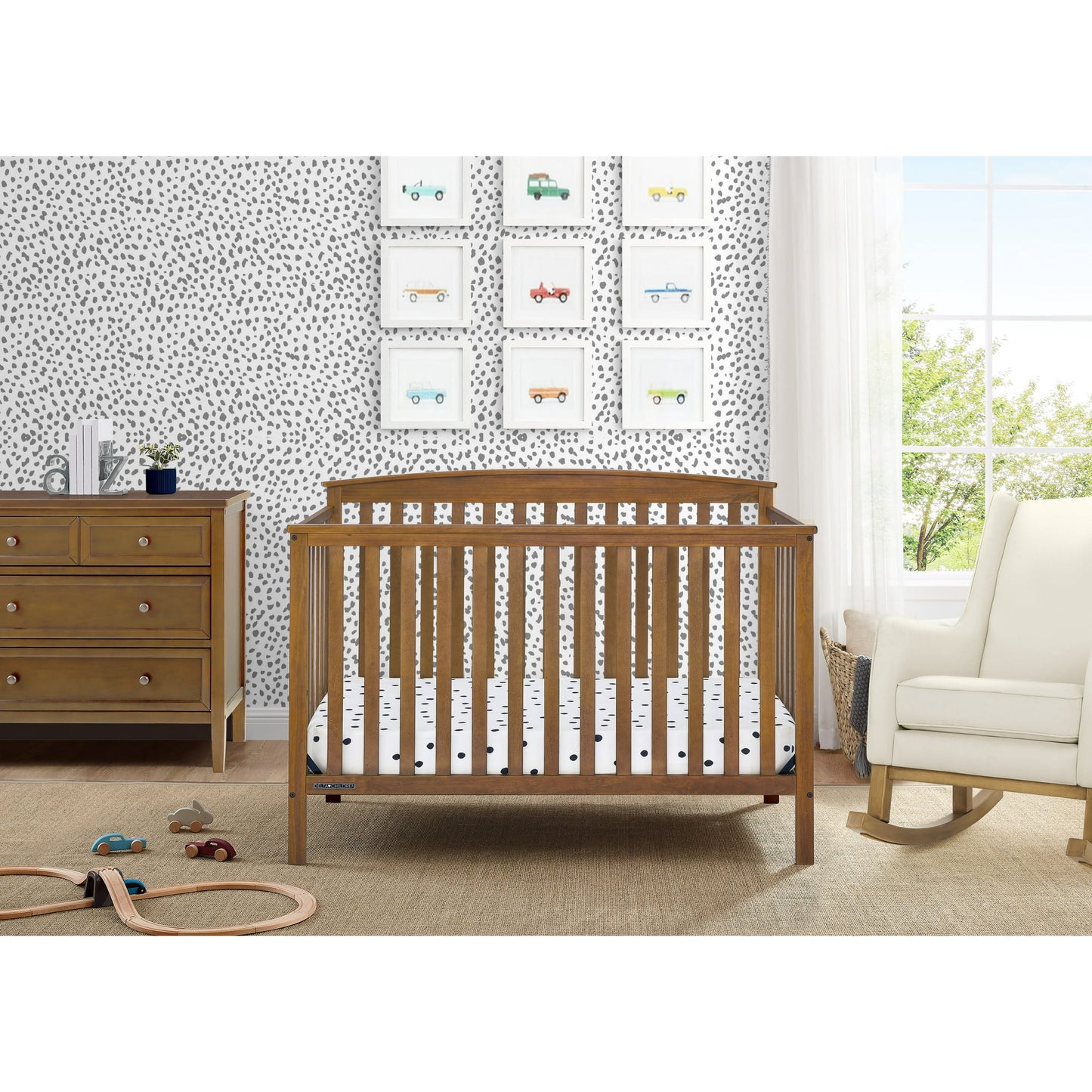 A nursery room with a wooden baby crib, a matching dresser, and a white rocking chair