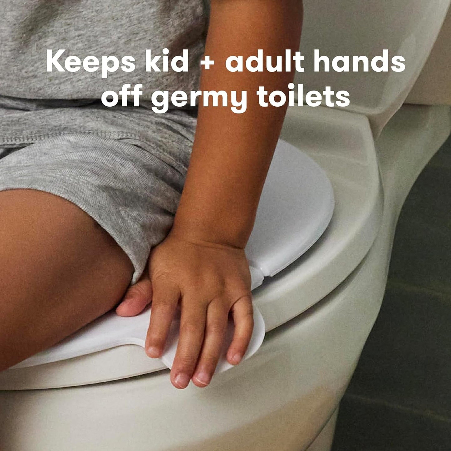 A child's hand on a white foldable potty seat placed on a toilet