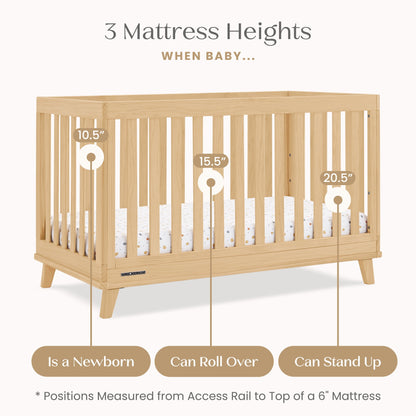 A light-colored wooden baby crib is shown with three adjustable mattress height positions for different stages of a baby's growth