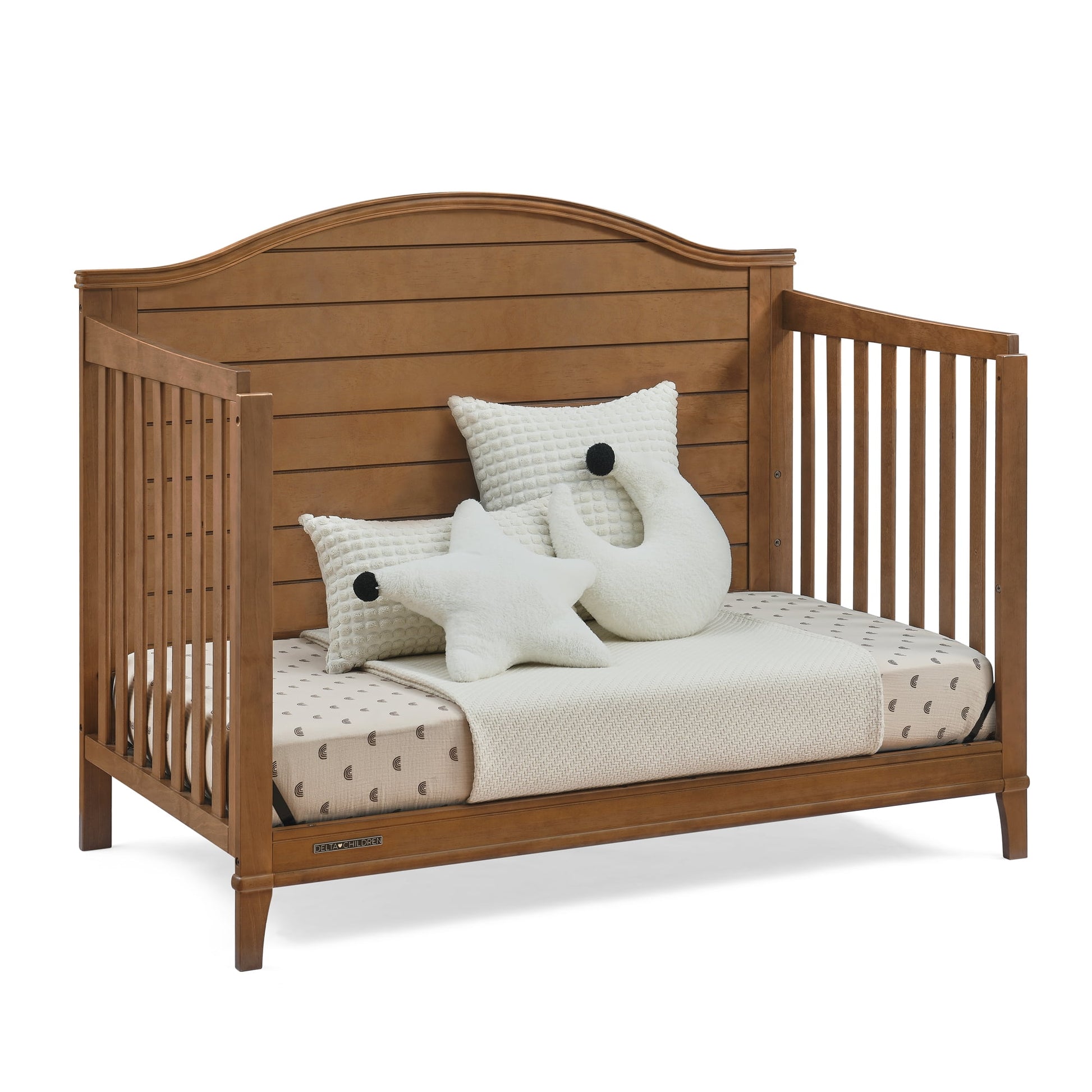 A wooden baby crib with mattress, patterned sheets, and decorative pillows
