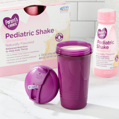 Strawberry-flavored Kids pediatric shake bottles, box, and a purple cup filled with shake with lid on a white surface