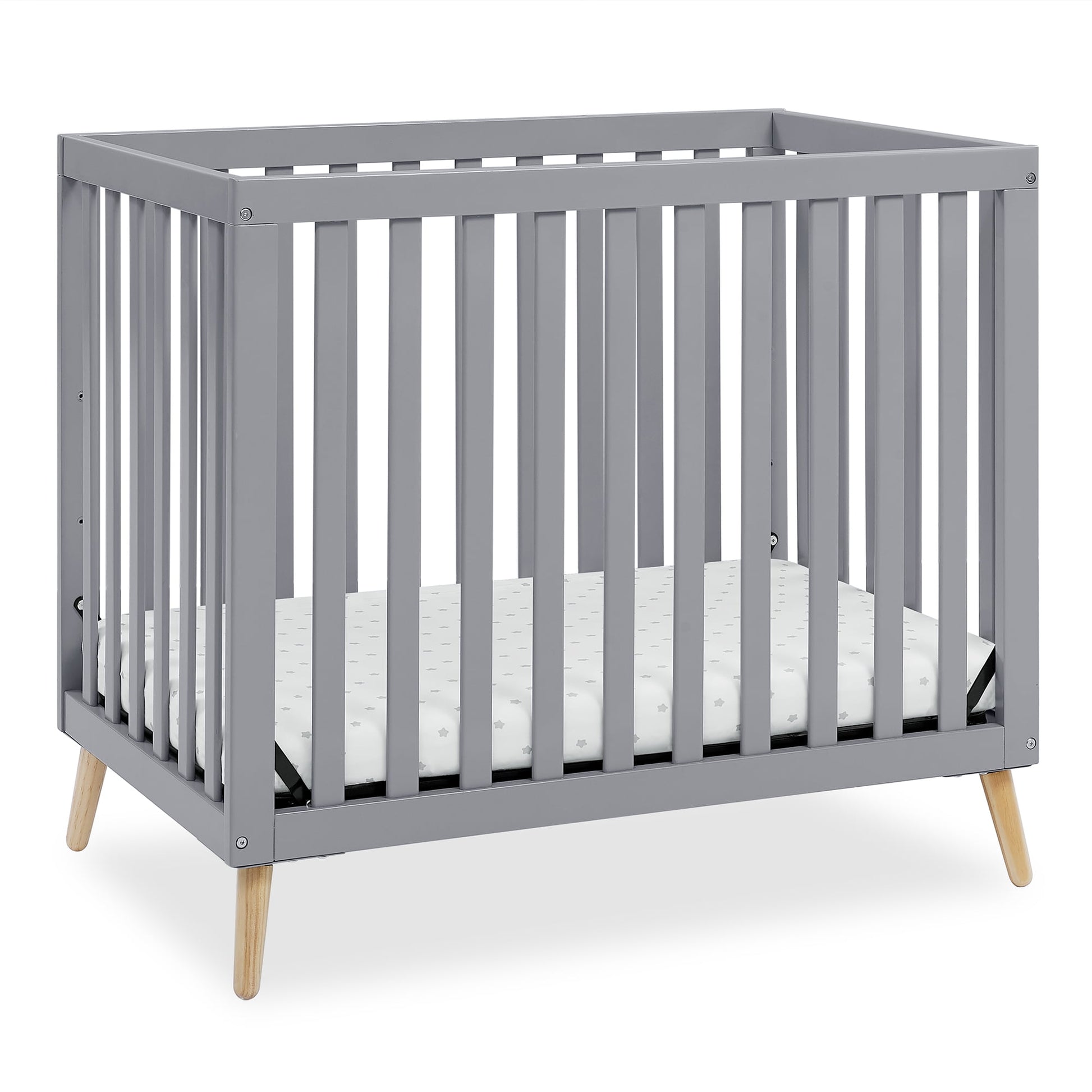 A grey baby crib with a mattress, featuring wooden legs and slatted sides