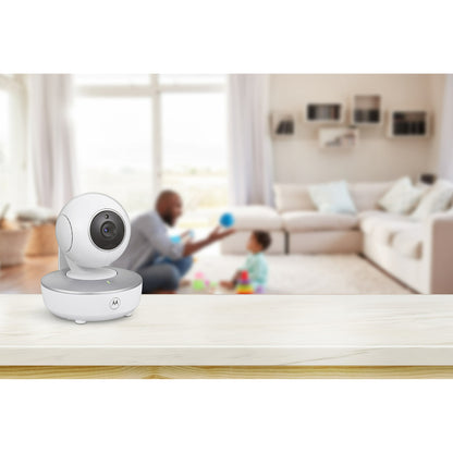 A baby monitor camera on a table with a blurred background of an adult and child playing