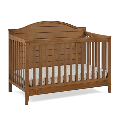 A wooden baby crib with a mattress inside, designed for infants and toddlers