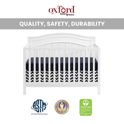A white convertible baby crib with a striped and patterned mattress, featuring safety certifications
