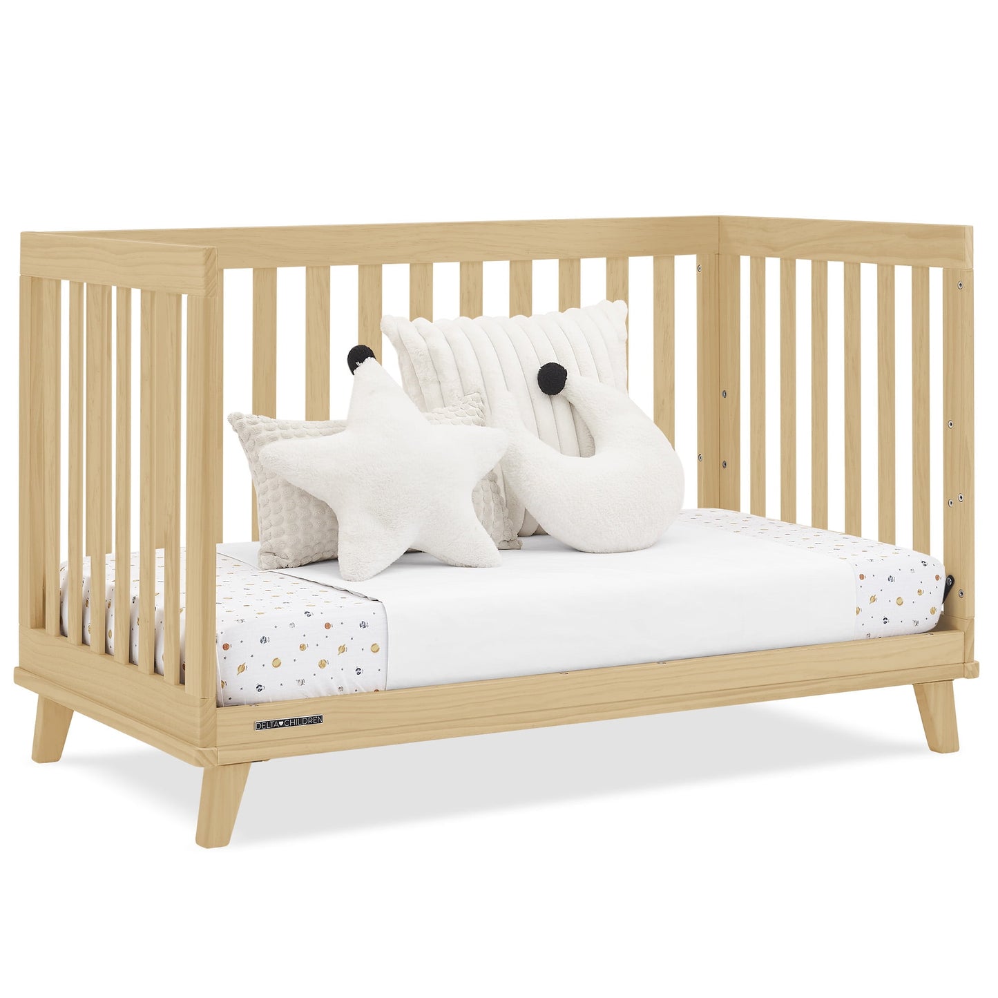A light wood baby crib with a white mattress, patterned sheet, and decorative pillows
