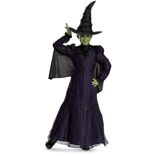Child wearing a witch Halloween costume with a black hat and green face paint on a white background