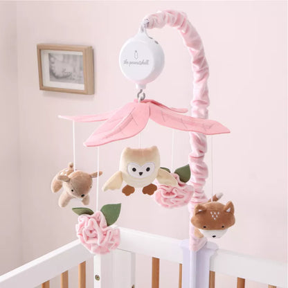 A pink musical baby crib mobile with woodland animals and flowers hanging over a white crib. 