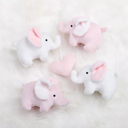 Pink and white elephant plush toys and a heart, part of a baby crib mobile