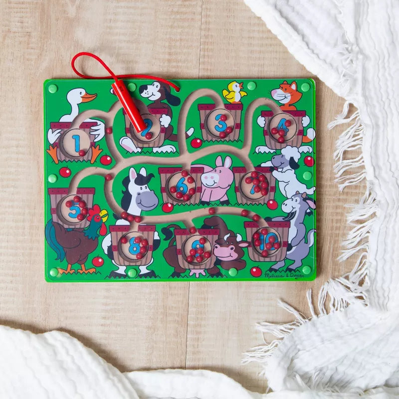 A magnetic wand number maze toy featuring farm animals, numbered baskets, and a red magnetic wand