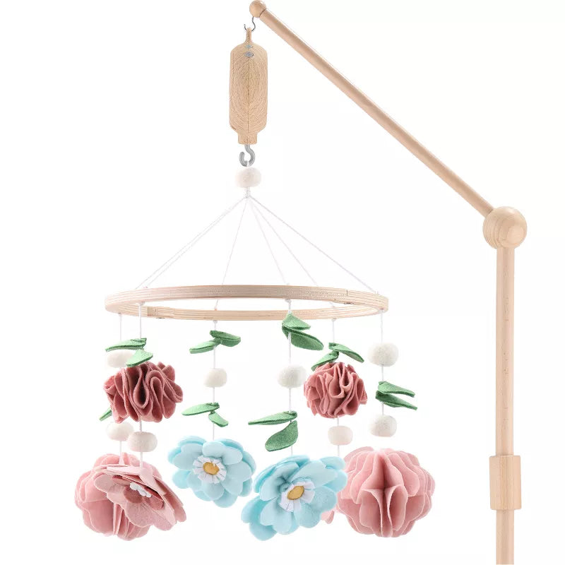 A wooden baby crib mobile featuring felt flowers and leaves suspended from a rotating ring