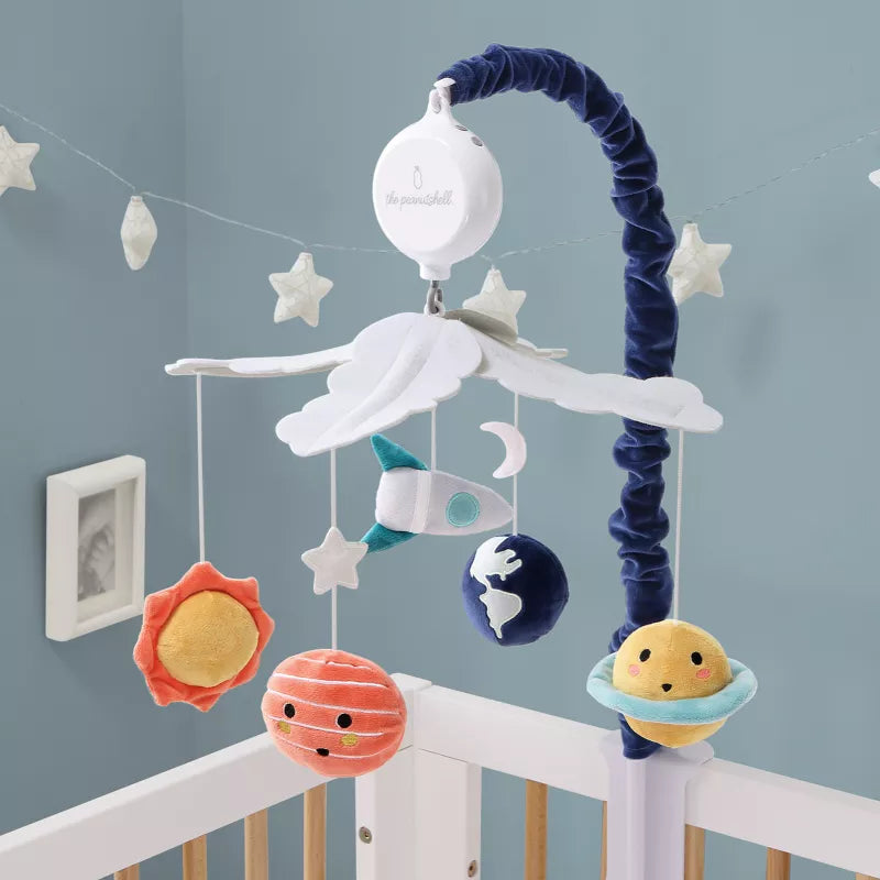 A baby crib mobile with hanging plush space-themed objects like planets, a rocket, and stars
