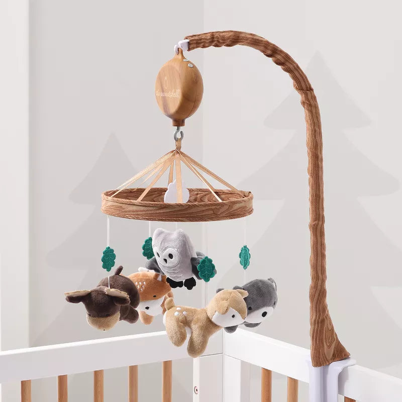 A musical baby crib mobile featuring hanging woodland animal figures like a deer, owl, and fox above a white crib