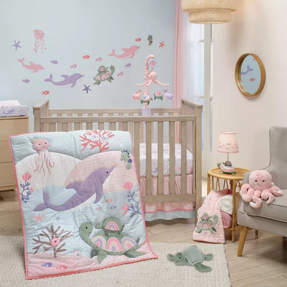 This image shows a nursery room with an ocean-themed baby crib bedding set, featuring a quilt, stuffed animals, and wall decals