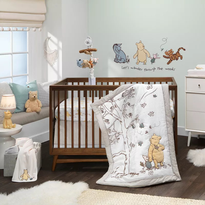 A Winnie the Pooh themed baby nursery with a crib, bedding, mobile, and wall decals