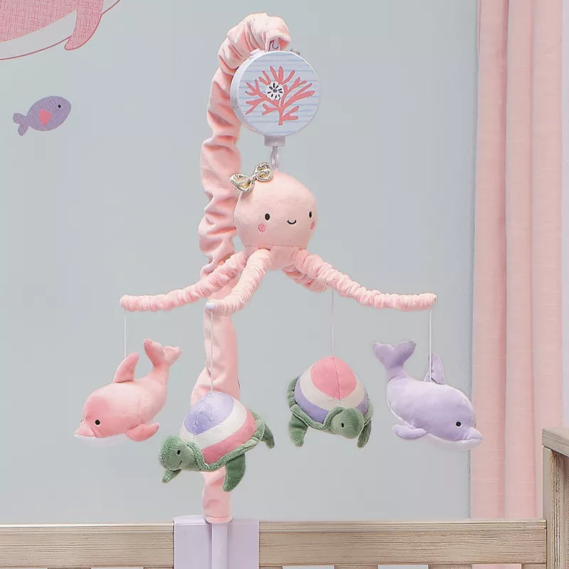 This image shows a baby crib musical mobile with plush sea creatures: a pink jellyfish, two dolphins, and two turtles