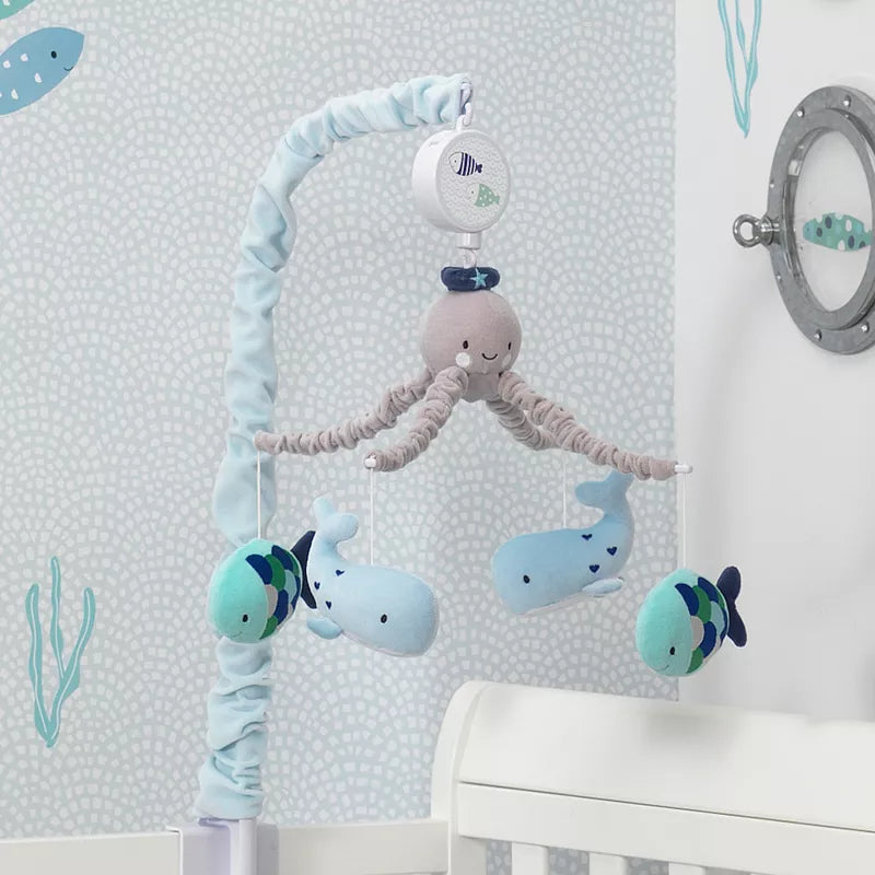 An ocean-themed musical baby crib mobile featuring an octopus, whales, and fish figures over a crib