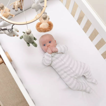 A baby lies in a crib with a musical mobile featuring plush safari animals hanging above