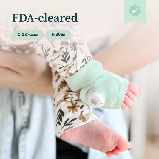Baby monitor sock with sensor strapped around infant’s foot; “FDA Cleared” and feature text visible above