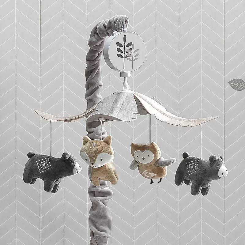 A baby crib mobile featuring plush woodland animals: bears, a fox, and an owl, against a patterned wall