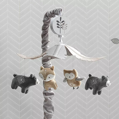 A baby crib mobile featuring plush woodland animals: bears, a fox, and an owl, against a patterned wall