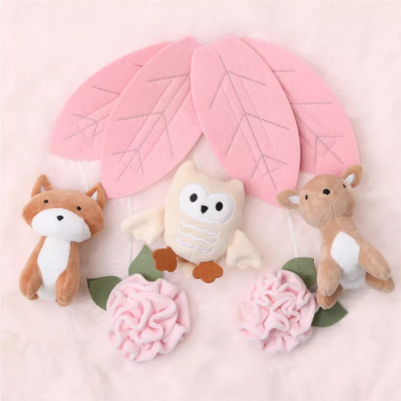 A baby crib mobile with plush fox, owl, deer, pink leaves, and flowers
