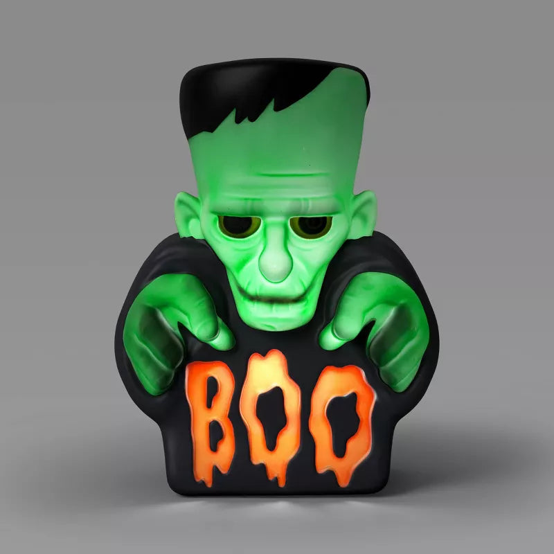 Halloween themed, Toy figure of a green monster with black hair and 'BOO' text on a gray background
