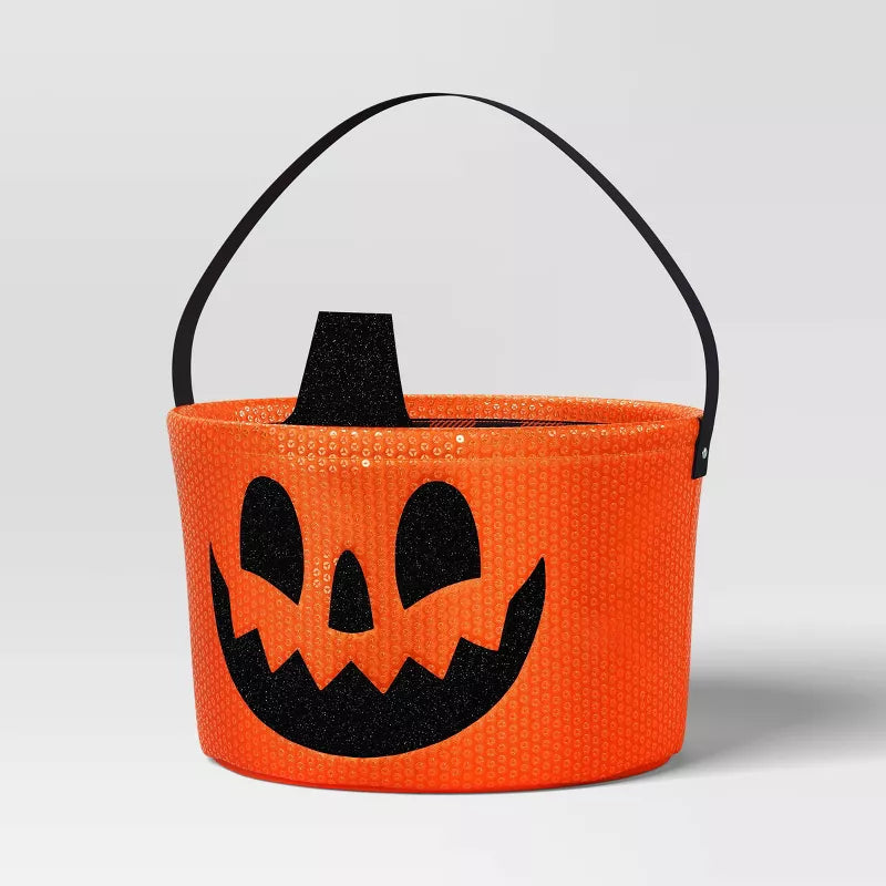 Orange Halloween candy bucket with black handle and jack-o'-lantern face design on a light gray background.