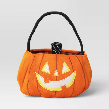 Orange pumpkin-shaped Halloween candy basket with a black handle on a light gray background