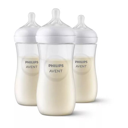 Three baby bottles filled with milk on a white background