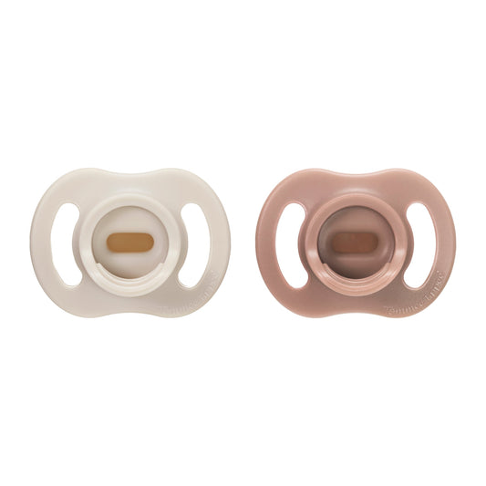 Two baby pacifiers, one white and one brown, on a white background