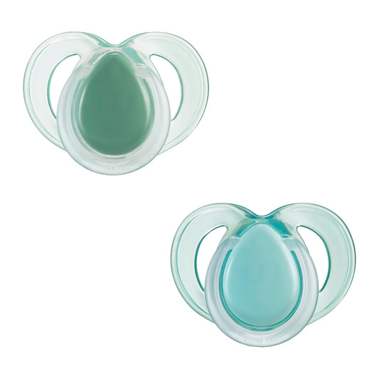 Two green baby pacifiers on a white background