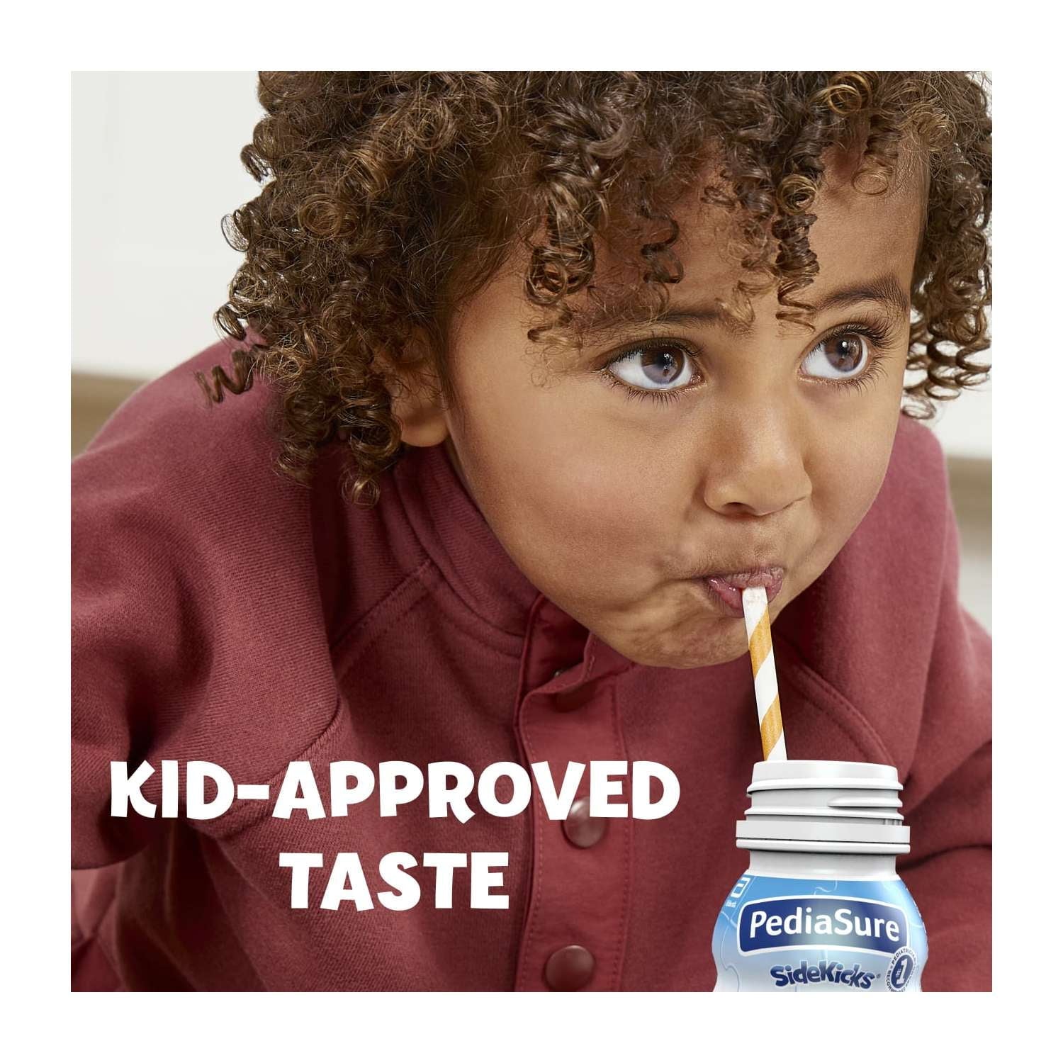 A child with curly hair drinks from a nutrition shake bottle with a straw