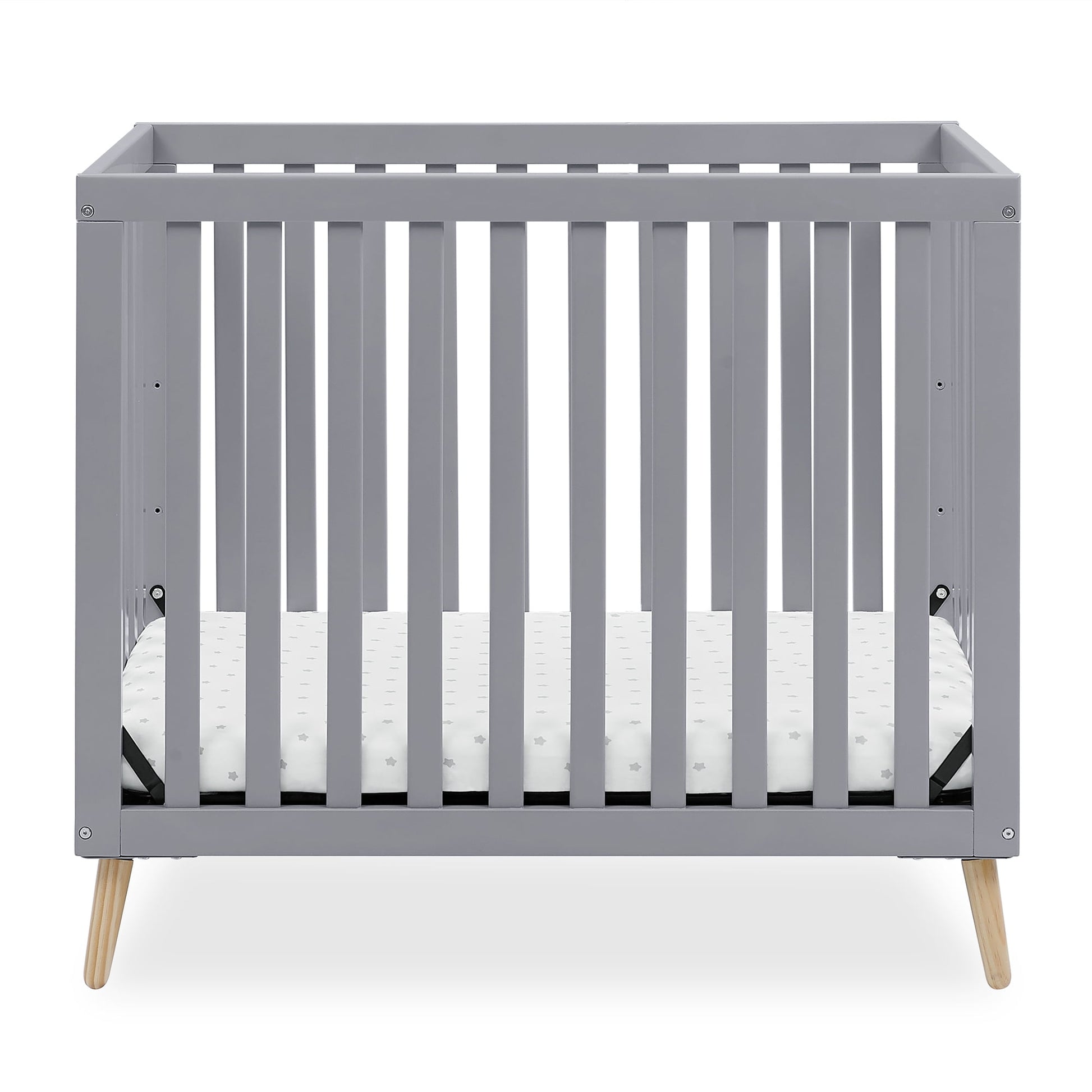 A grey baby crib with a white mattress, featuring natural wood splayed legs
